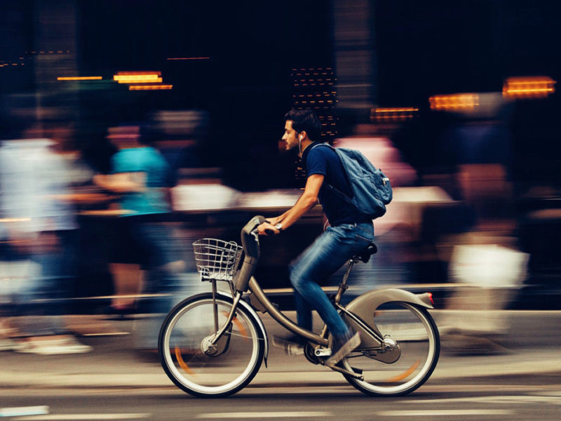 Mann fährt schnell auf einem Fahrrad vor einer Menschenmenge