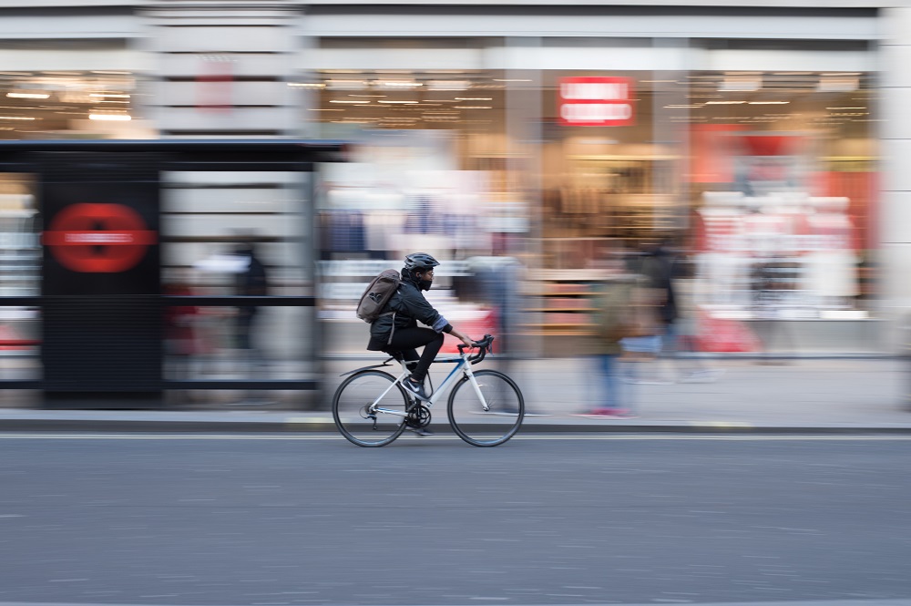Schnell fahrender Radfahrer vor einem Geschäft
