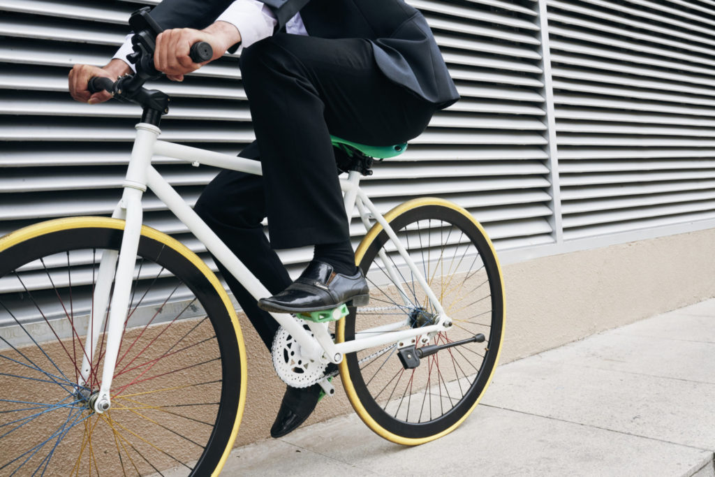 Weißes Fahrrad mit gelben Rädern und einem fahrenden Business-Mann